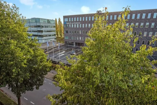 Kantoorpand van Boele & van Eesteren aan de Laan van Vredenoord, deels omgeven door bomen.